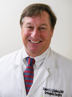 A Man Wearing A Suit And Tie Smiling At The Camera