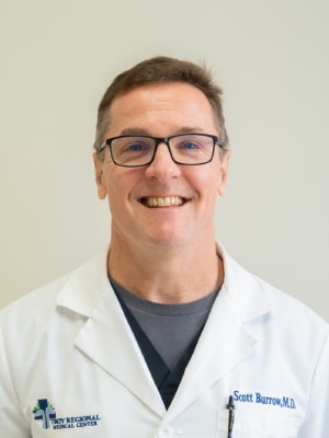 a man wearing glasses and smiling at the camera