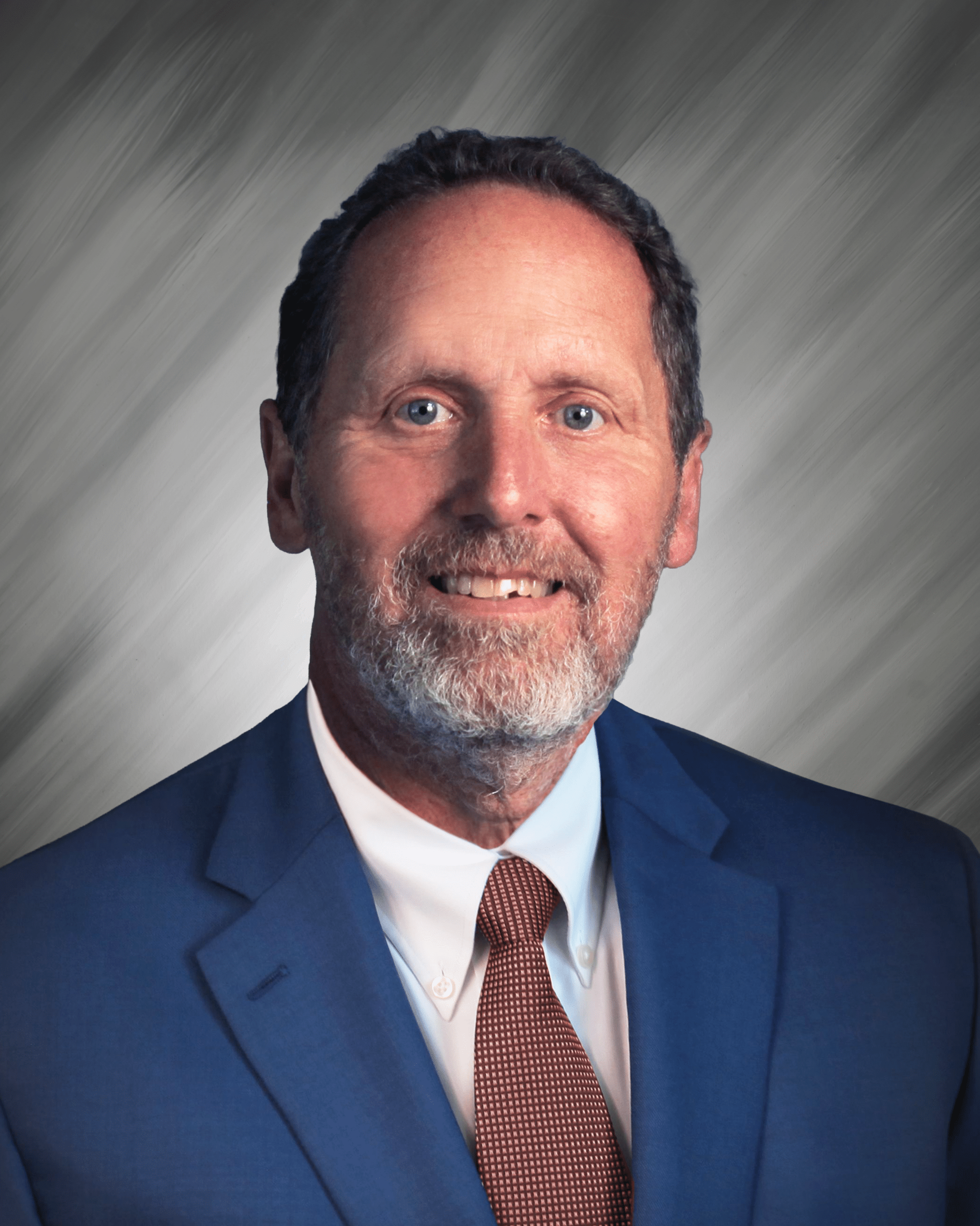 A man in a blue suit with a red tie against a gray background.