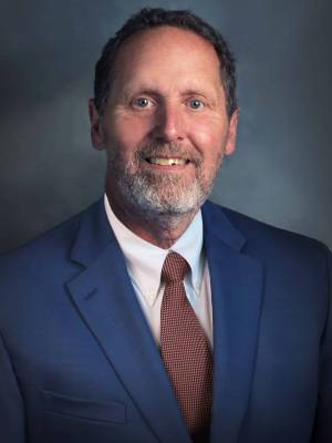 a man wearing a suit and tie smiling and looking at the camera