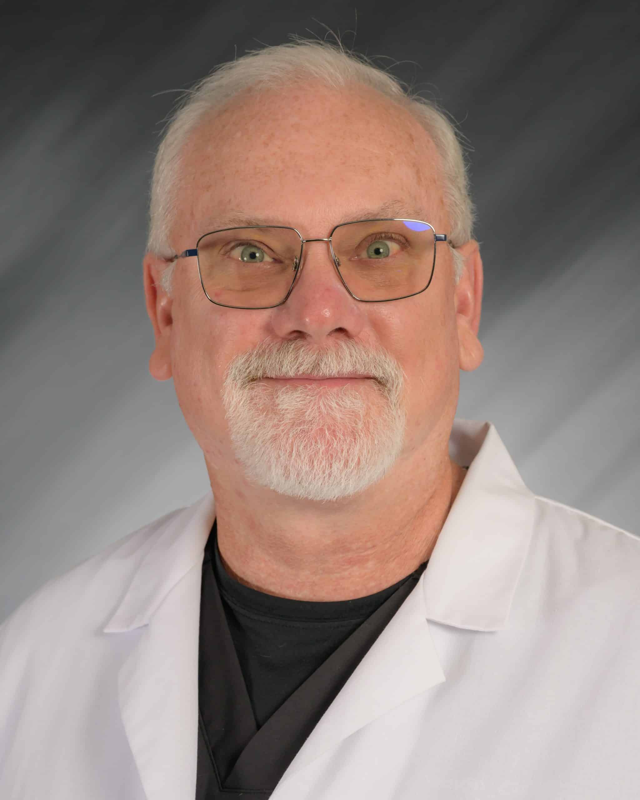 Troy University A person in a lab coat and glasses with a professional expression.