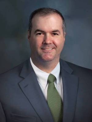 a man wearing a suit and tie smiling at the camera