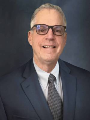 a man wearing a suit and tie smiling at the camera