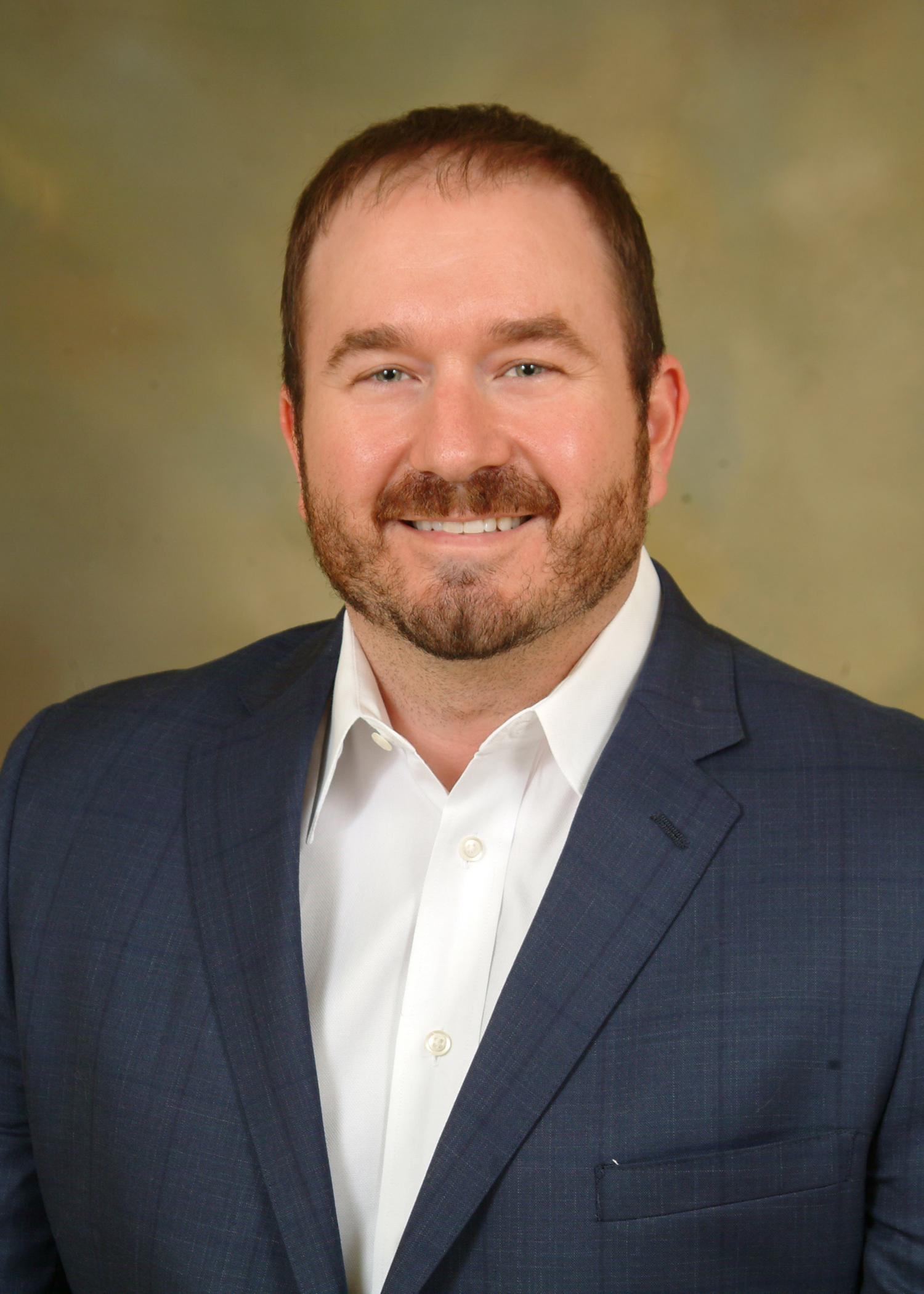 a man wearing a suit and tie smiling at the camera