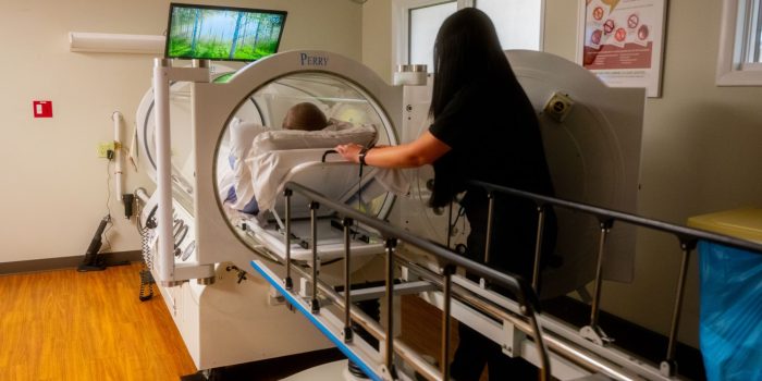 A medical professional assisting a patient in a hyperbaric chamber.