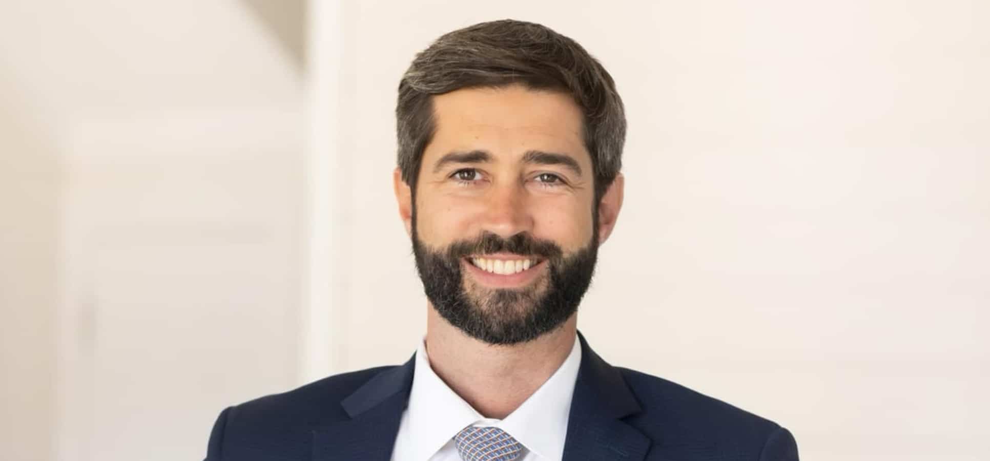 a man wearing a suit and tie smiling at the camera