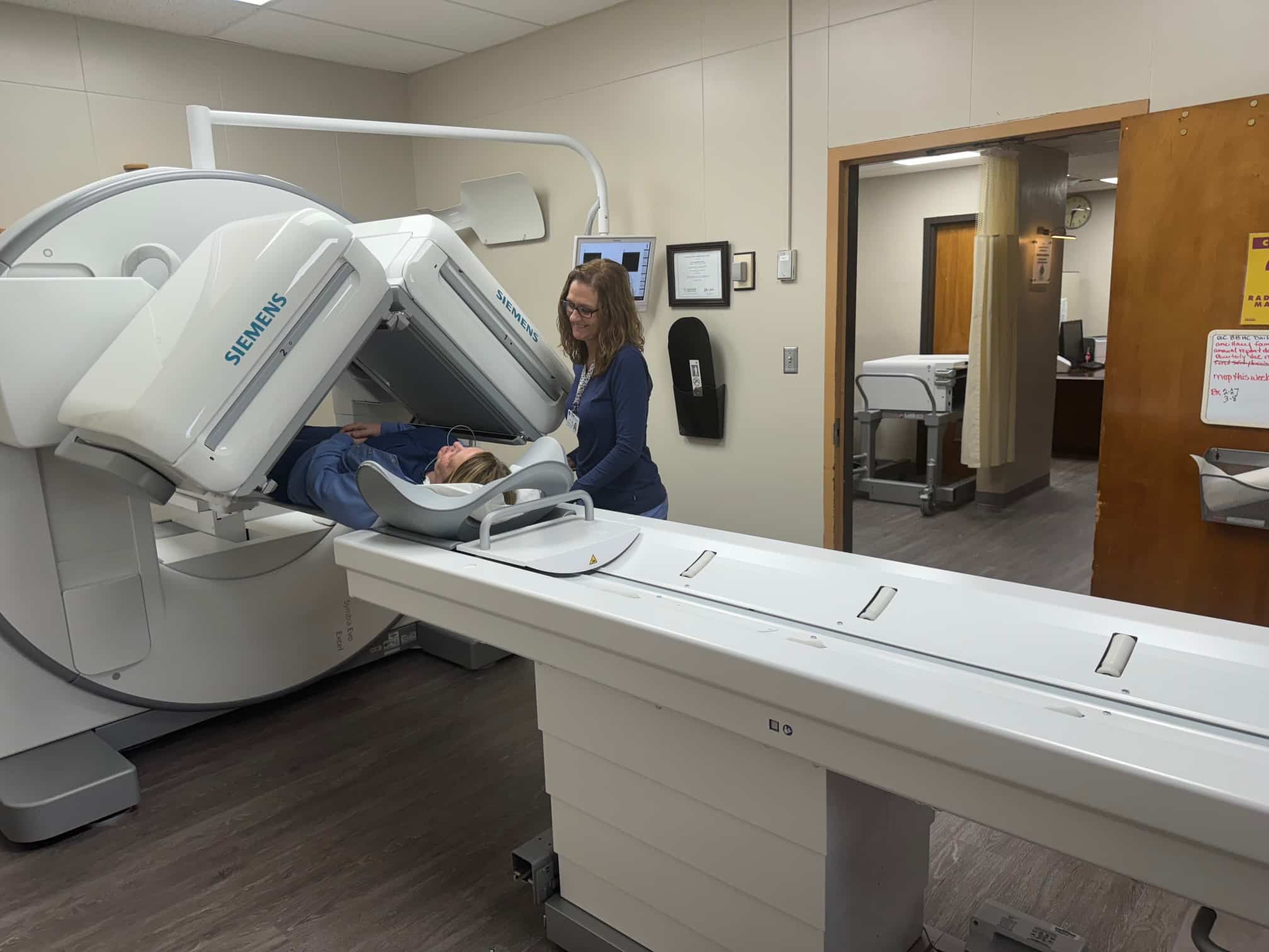 A person undergoing a scan with a Siemens medical imaging device in a hospital room.