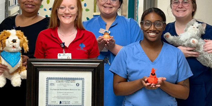 a group of people standing next to a teddy bear posing for the camera