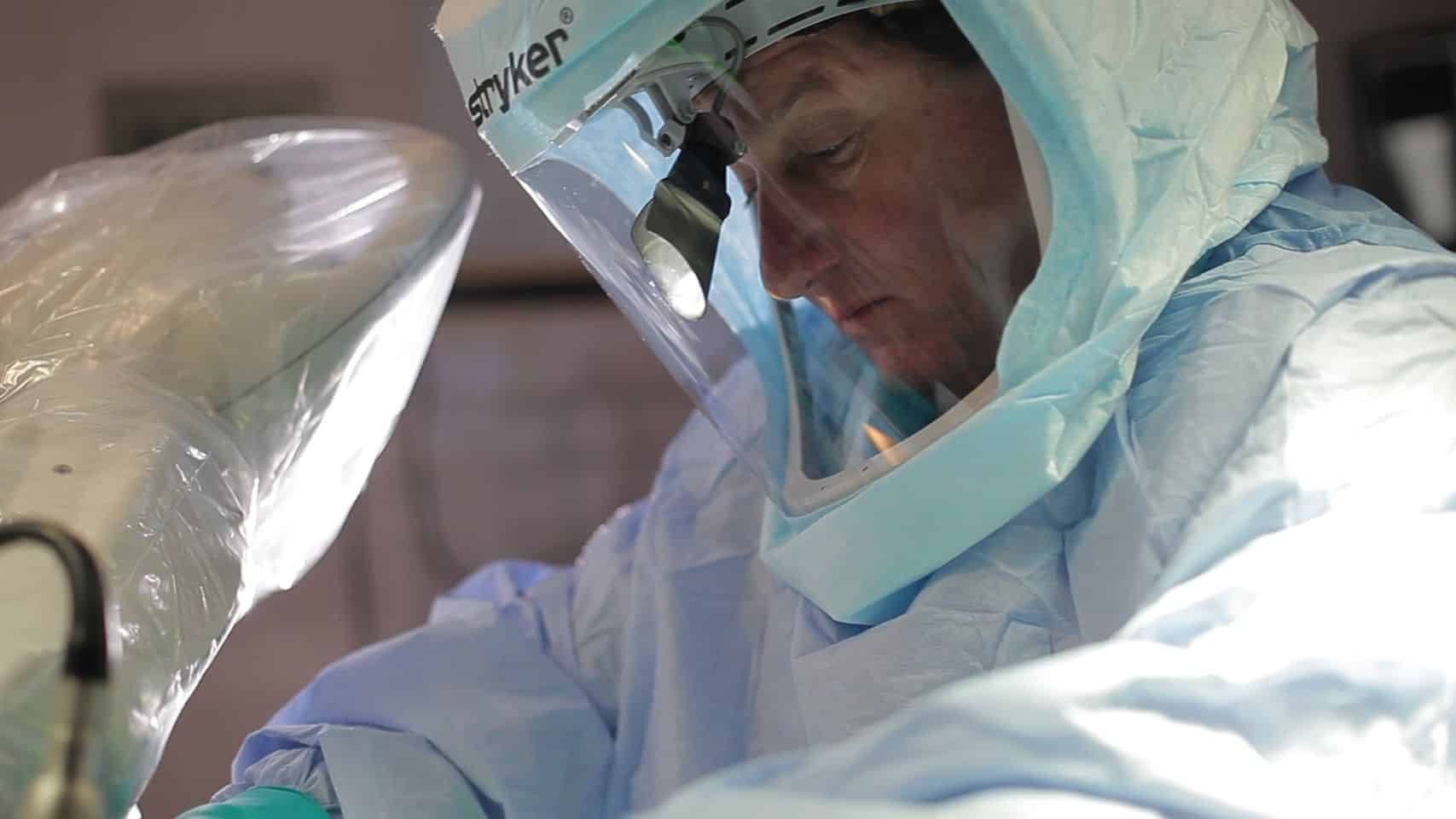 Surgeon in protective gear performing a medical procedure.