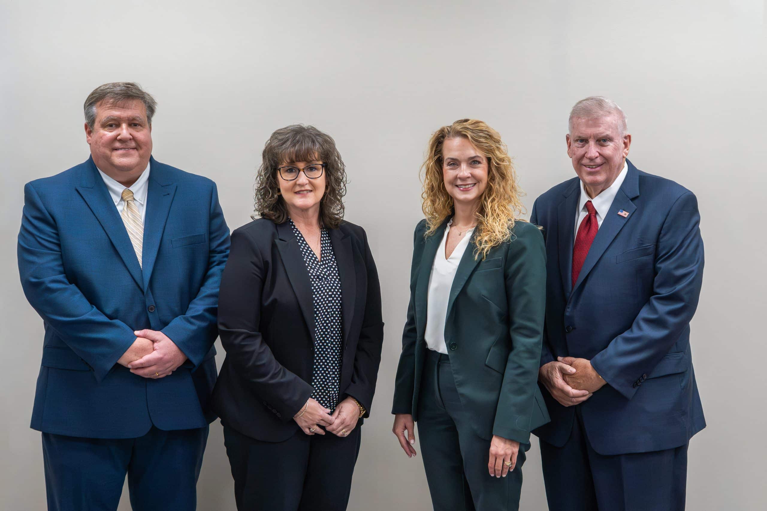 Group of four people in business attire standing in a line.