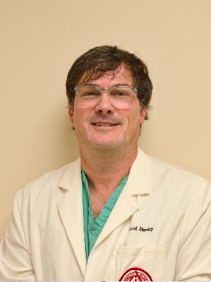 a man wearing glasses and smiling at the camera