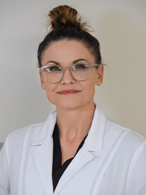 A doctor in a white coat with glasses and hair in a bun.
