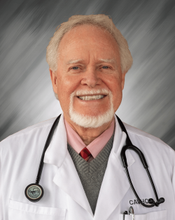 A man in a white coat with a stethoscope, smiling in front of a gray background.