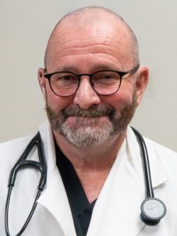 A smiling man in glasses and a white lab coat with a stethoscope.