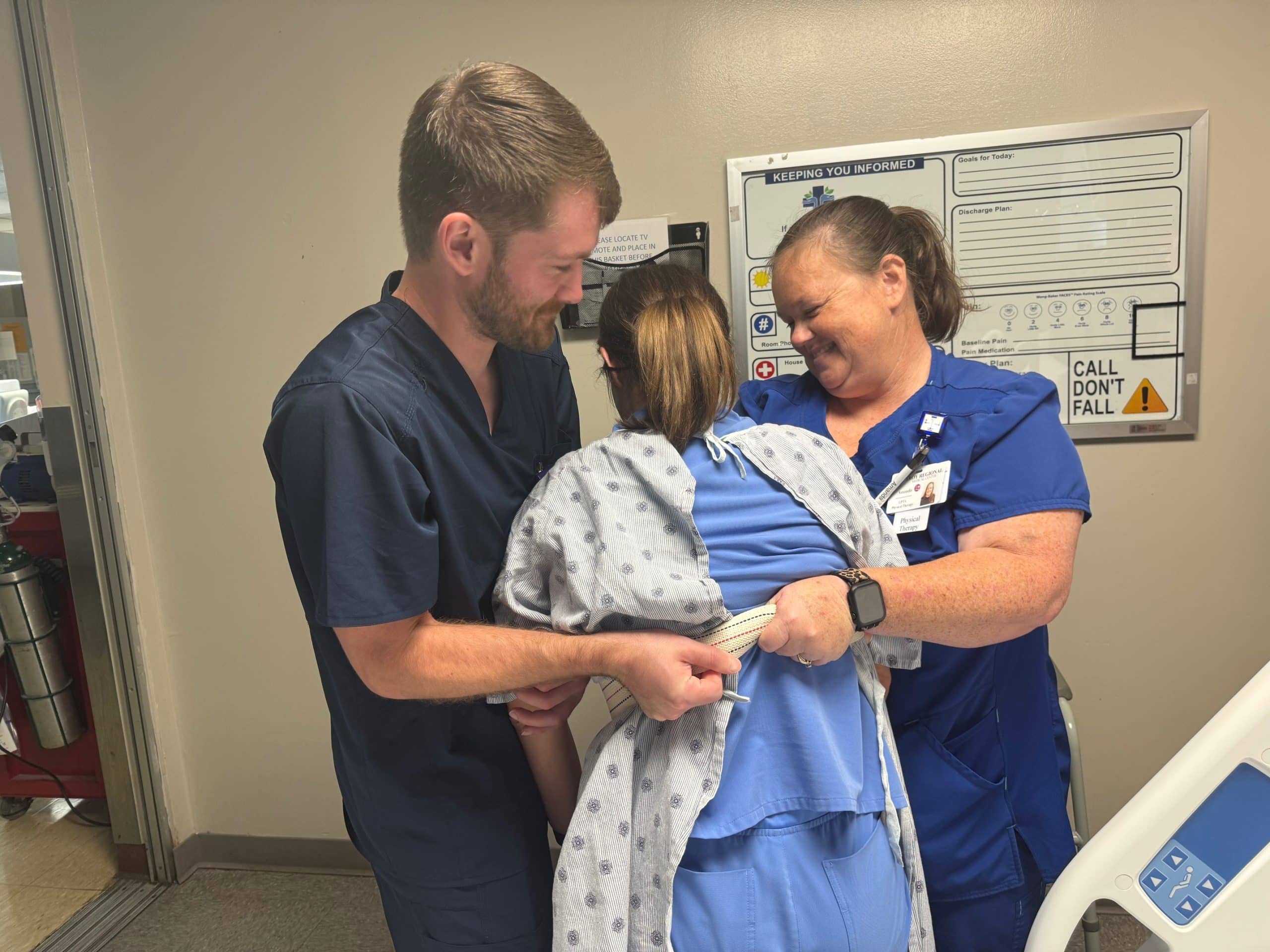 Healthcare workers assist a patient in a hospital setting.