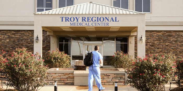 Person in scrubs entering Troy Regional Medical Center.