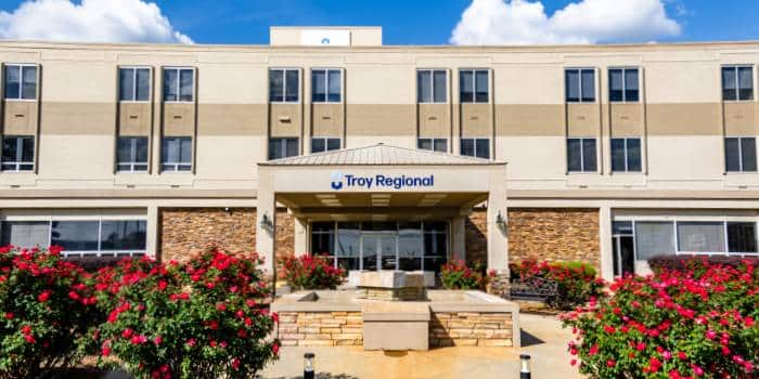 Troy Regional building exterior with red flowers in front.