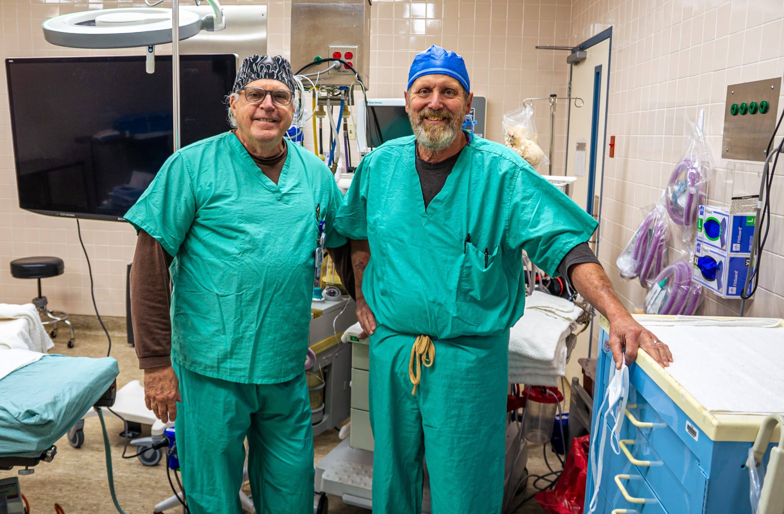 Two CRNAs in green scrubs standing in an operating room.