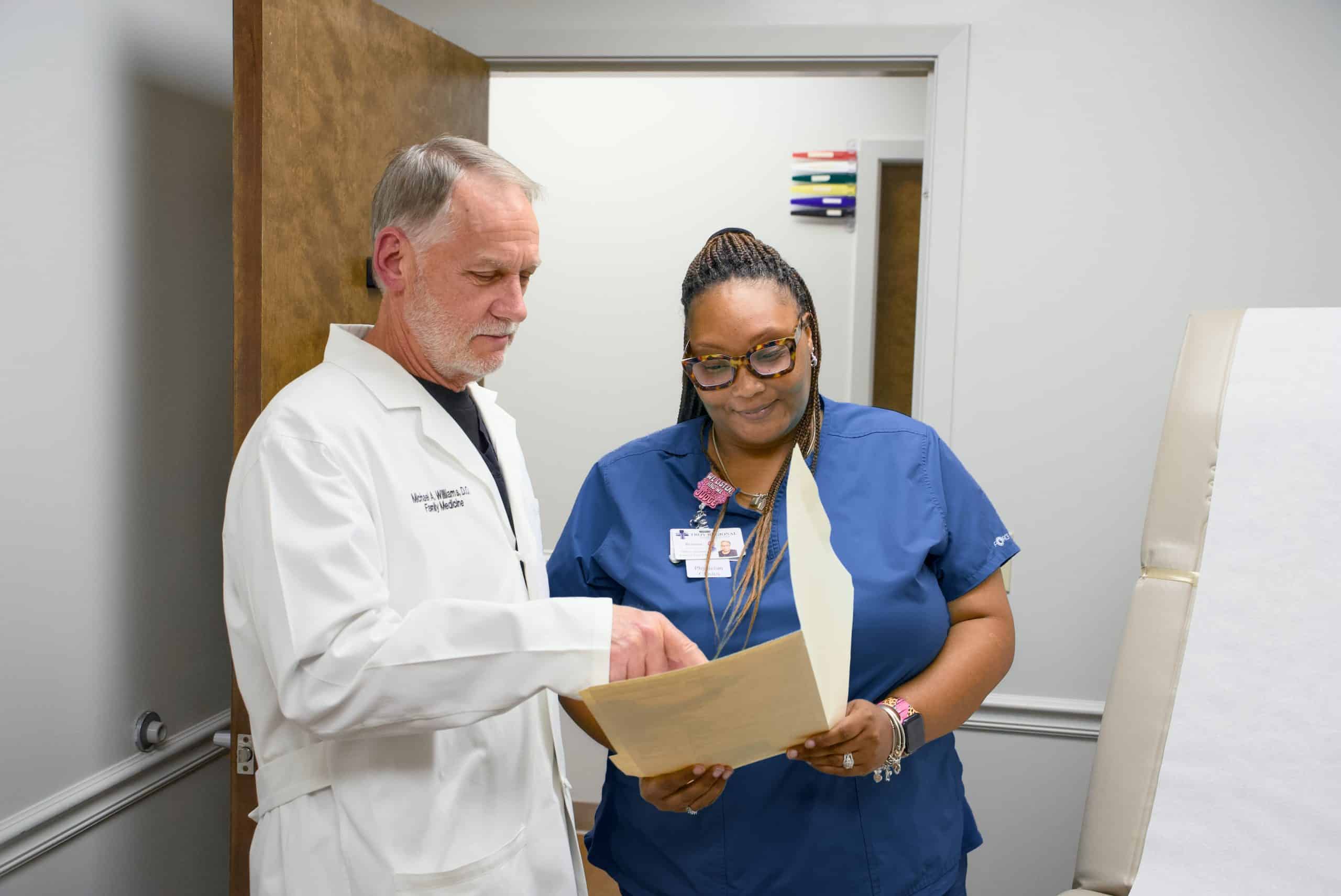 Doctor and nurse reviewing patient files in a medical office setting.