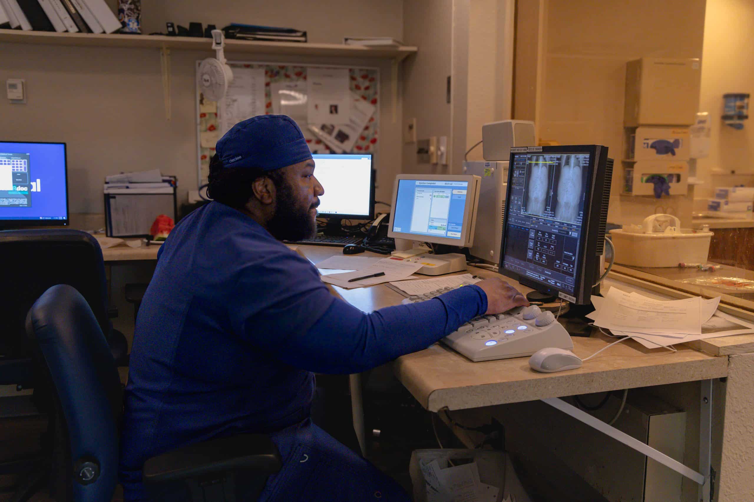 Medical professional analyzing scans on a computer in a hospital room.