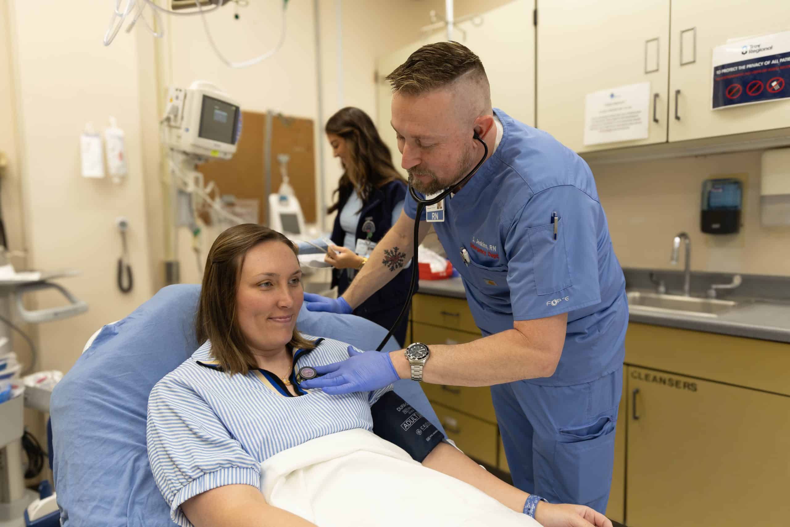 Nurse examining a patient with a stethoscope in a hospital room.