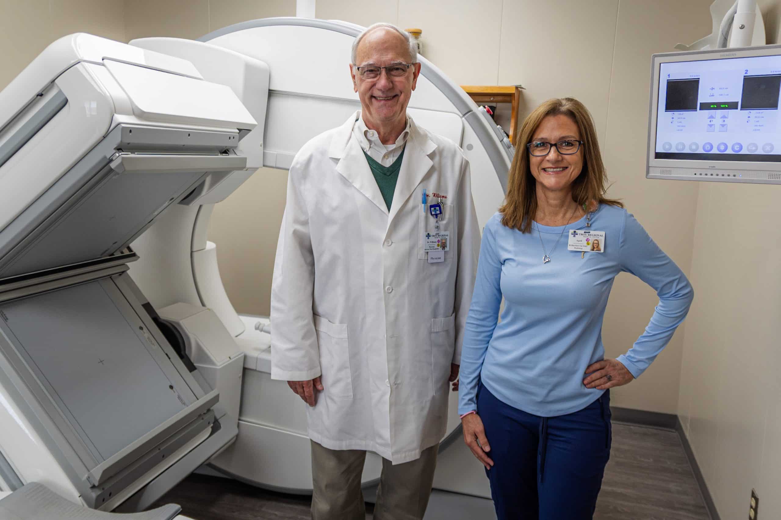 Two medical professionals in a lab with medical equipment and a monitor.