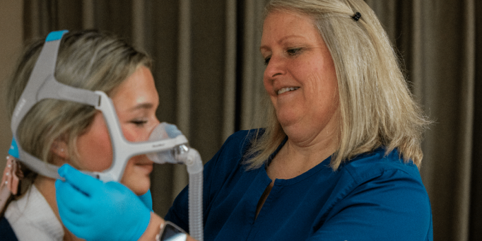 Healthcare worker fitting a woman with a CPAP mask.