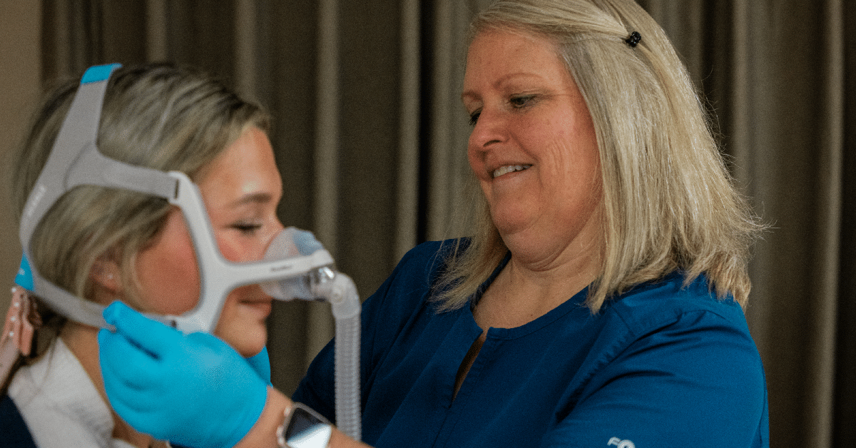Healthcare worker fitting a woman with a CPAP mask.