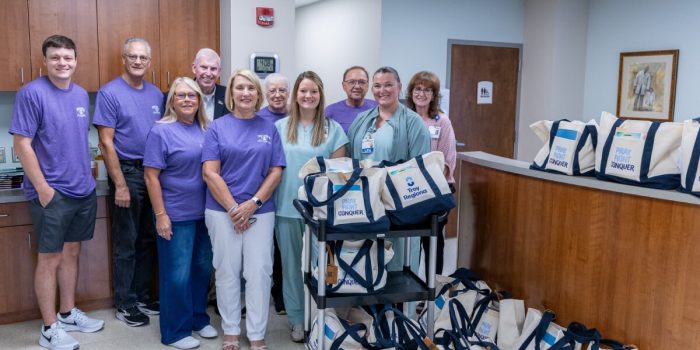 Group of people standing in a hospital with gift bags labeled Pray, Fight, Conquer.