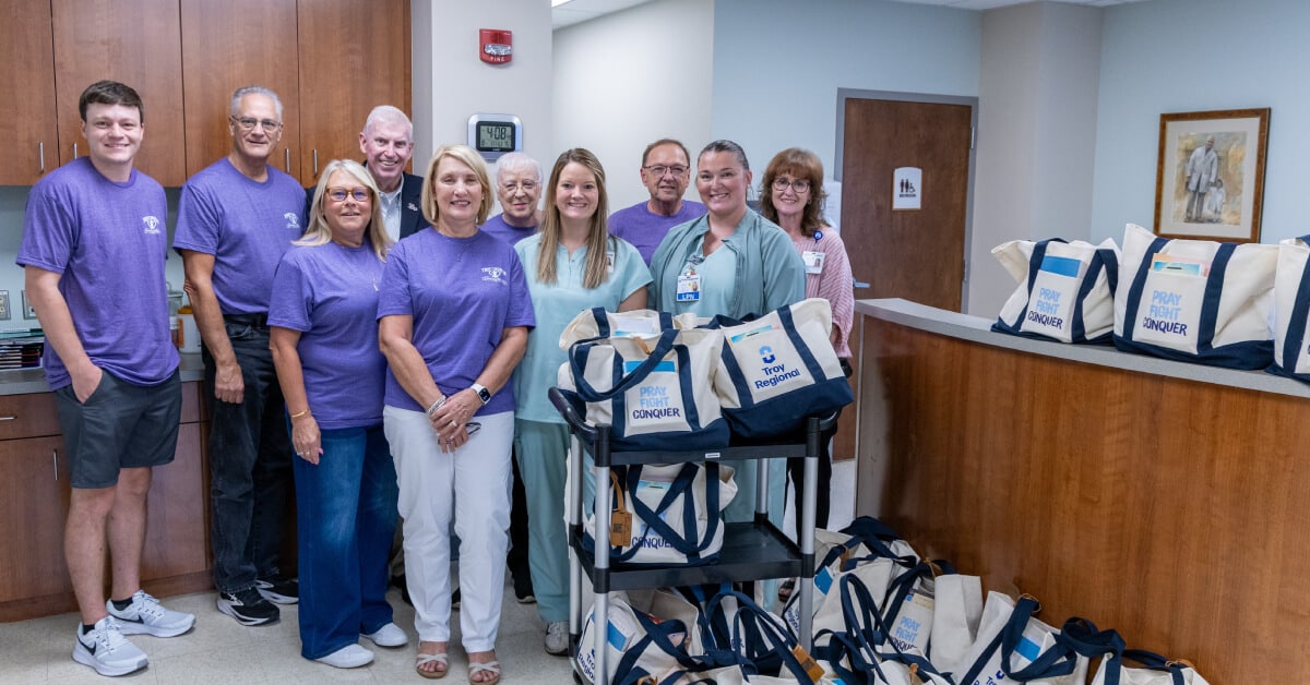 Group of people standing in a hospital with gift bags labeled Pray, Fight, Conquer.